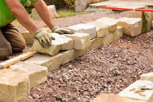 Man Landscaping With Natural Stones Building Of A Dry Stone W
